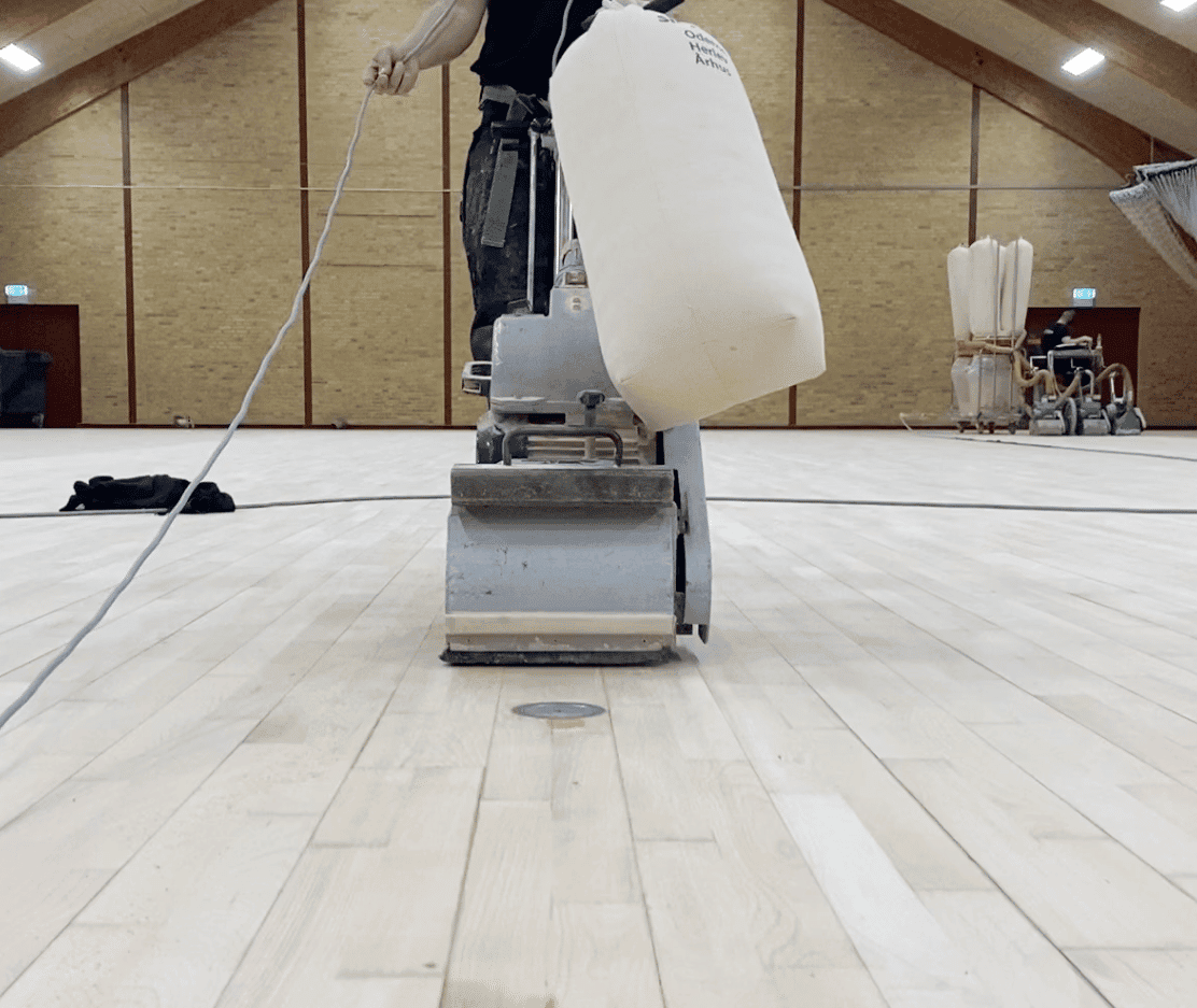 Professionel gulvafslibning i sportshal med maskine